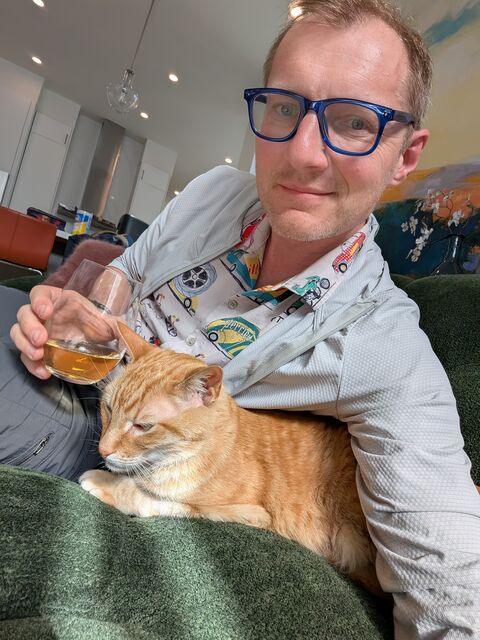 Dumitru Erhan relaxing on the couch with an orange cat